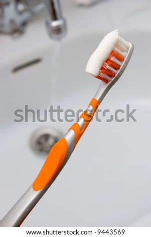 A nice picture of a orange toothbrush above the sink.