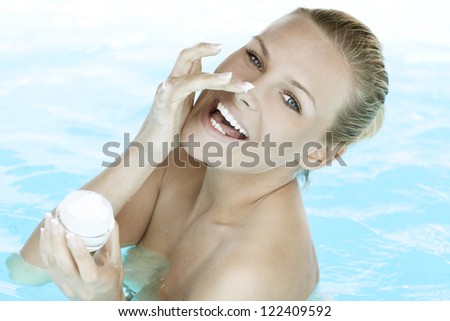 Smiling woman applying cream on her face