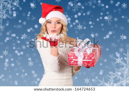 Christmas woman in santa hat with a gift in hand on blue background.