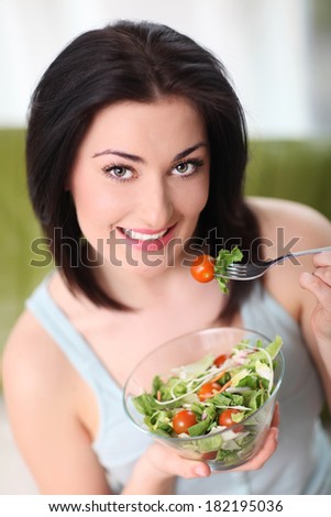 Happy woman eating organic salad. Woman keeping a diet with green salad.
