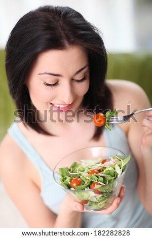 Happy woman eating organic salad. Woman keeping a diet with green salad.