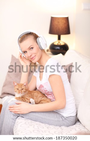 Attractive woman with cat  listens to music