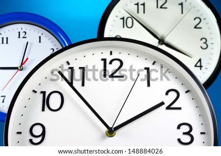 Using time resourcefully. Three wall clocks on blue background.