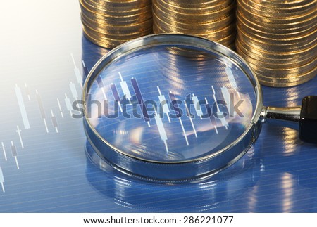 Chart, magnifying glass and pile of coins. Analyzing chart with magnifying glass. Market research study.