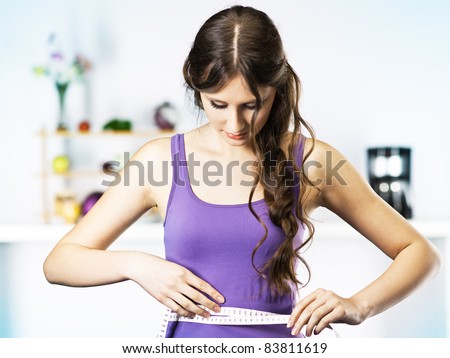 Woman Measuring Waist in kitchen