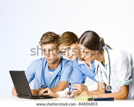 Doctor and nurses discussion at doctors office at laptop desk