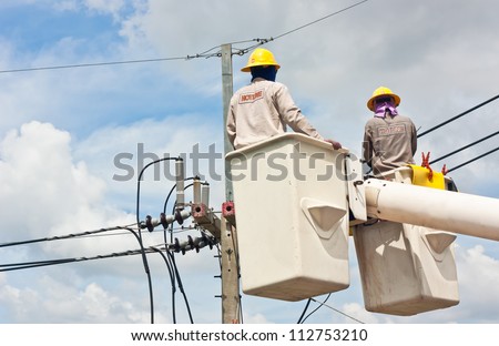 Electrical utility worker in a bucket fixes a problem with a power line.