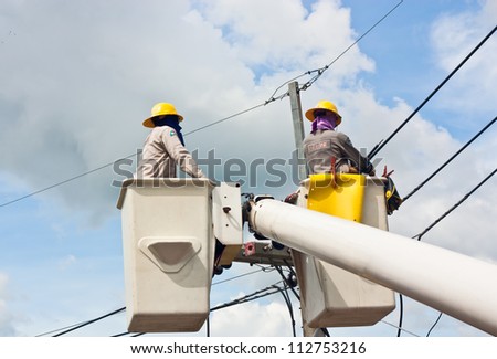 Electrical utility worker in a bucket fixes a problem with a power line.