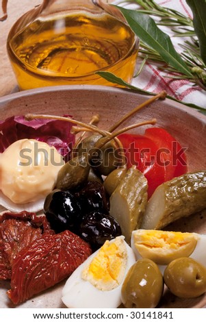 Italian antipasti, a plate of black and green olives, capers, egg, cornichon, sun dried tomatoes, radicchio and homemade mayonnaise