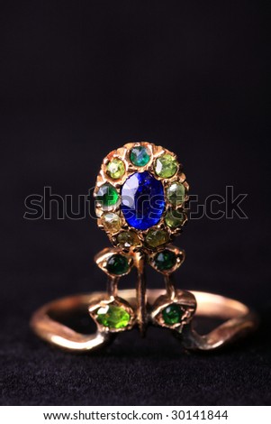 Antic golden ring in the form of a flower with sapphire and emeralds on a black  background