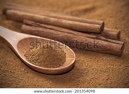 Spoon full of powdered cinnamon, with cinnamon sticks