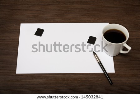Blank sheet of paper, pen and cup of coffee on dark wooden office desk.