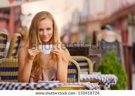 Blond girl drinking coffee and smiling.