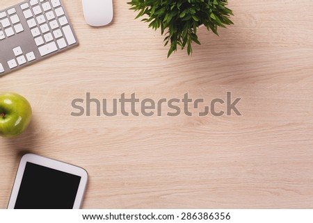 Office equipment such as pc keyboard, tablet, mouse on wooden office desk.
