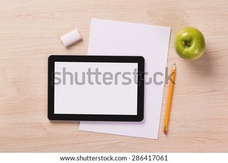 Office equipment such as digital tablet, notebook with pencil and paper on wooden office desk.