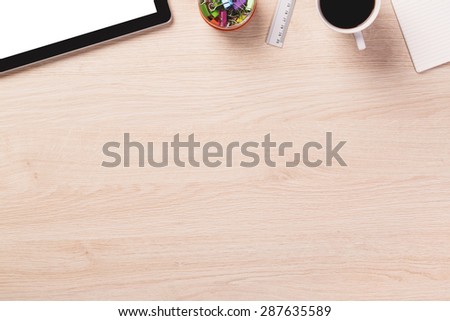 Empty space next to office equipment such as digital modern tablet, ruler, mug of coffee and paper on bright wooden office desk.