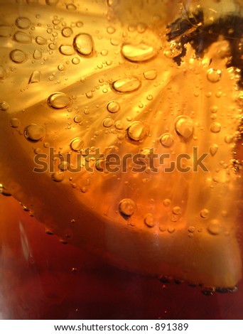 Close up of bubbles on a lemon slice in a cold glass of fizzy pop.