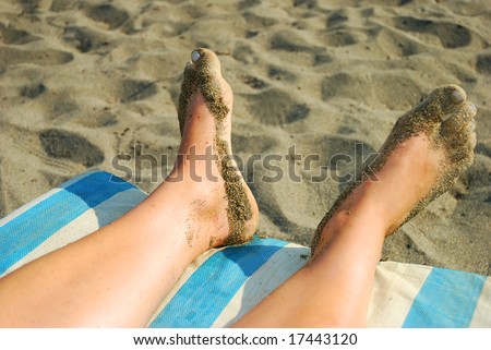 Pair of a woman\'s feet over the chair on the beach