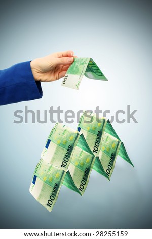 A hand is building a tower with money folded.