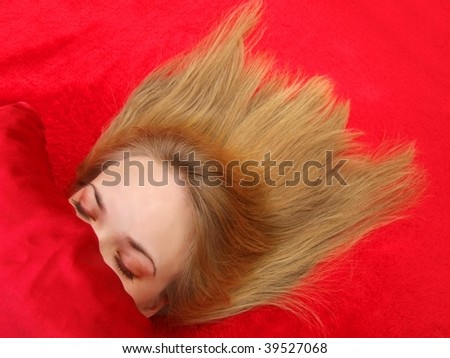 pretty girl asleep in a bed with red satin sheets, her hair spread out