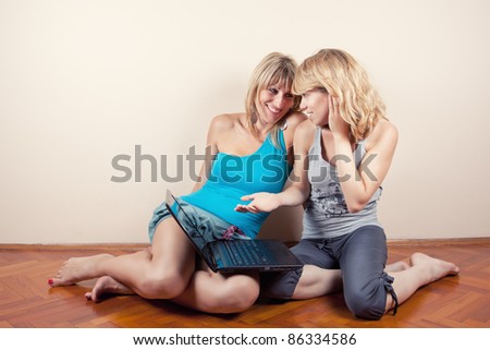 Two young girls siting on floor of room with laptop