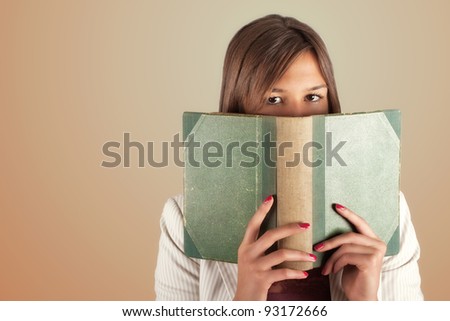 Girl hiding behind green big book