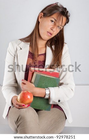 Teacher with book and apple seating on desk