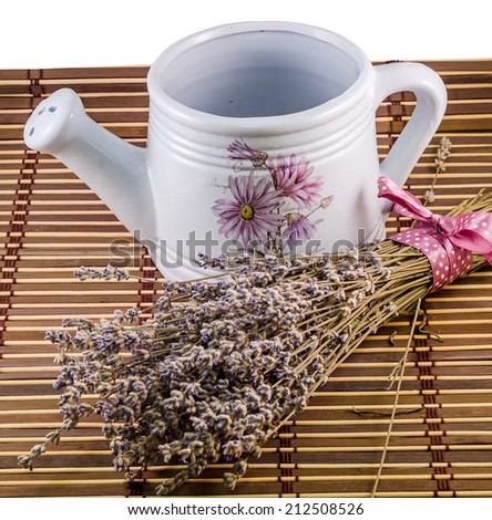 White sprinkler, watering can and a bouquet of Lavandula flowers (common name lavender) standing on a wood cover.