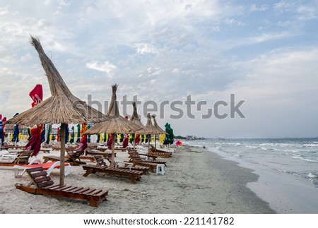 The Black Sea shore, sea side with sand, umbrellas, sun beds and water, blue sky