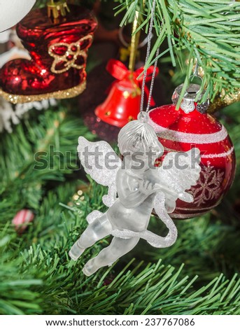 Detail of green Christmas (Chrismas) tree with colored ornaments, globes, stars, Santa Claus, Snowman, red boots, shoes, candles, bells, white transparent angels, snow flakes and candy sticks.