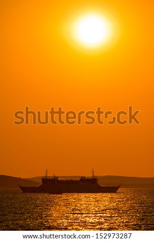 Ferry boat under golden sun on sea, vertical view