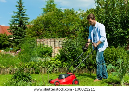 Young man is mowing the lawn in summer with a mowing machine