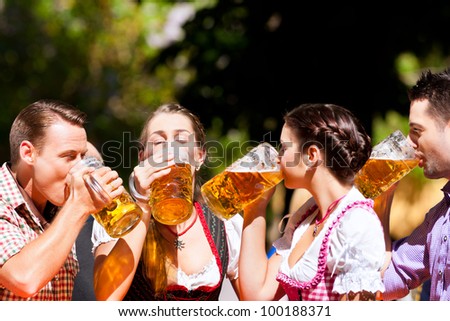 Two happy couples sitting in Bavarian Beer garden and enjoy the beer and the sun
