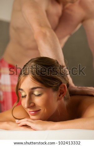 Woman enjoying a wellness back massage in a spa, she is very relaxed (close-up); the masseur could be her boyfriend