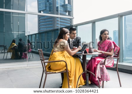 Three Indian business people with worried facial expression talking during break at work