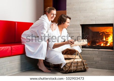 Young couple sitting in bathrobe for open fireplace, it is very romantic - stock photo