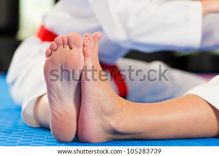 Woman in martial art training in a gym, she is stretching and warming up