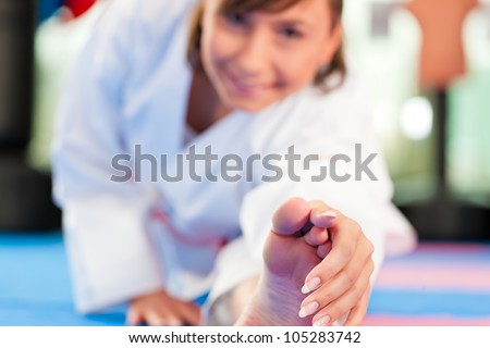 Woman in martial art training in a gym, she is stretching and warming up
