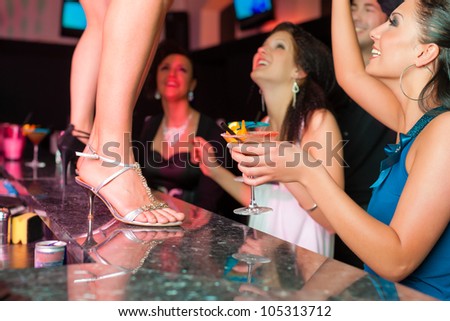 People having a party in club or bar, one woman is dancing on the table