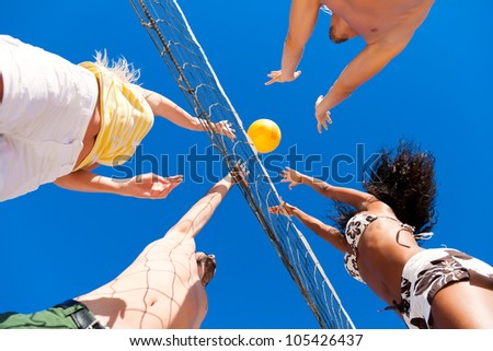 Players doing summer sports trying to block a dangerous attack in a beach volleyball game