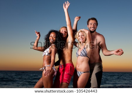 People (two couples) on the beach having a party, having a lot of fun in the sunset