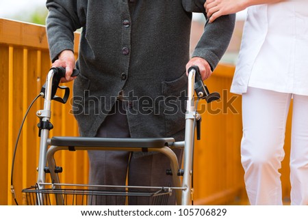 Young nurse and female senior with walking frame, the caretaker helping her