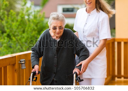 Young nurse and female senior with walking frame, the caretaker helping her
