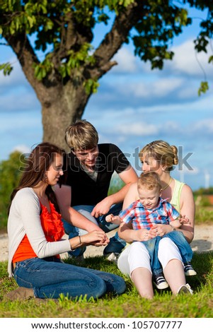 Family - Grandmother, mother, father and child sitting and playing in garden