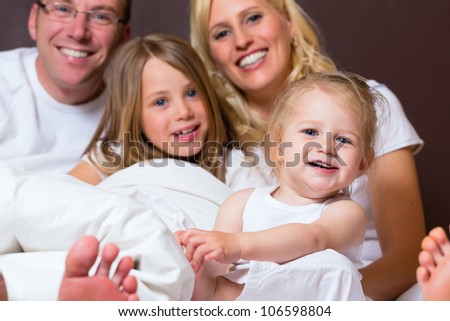 Group picture of a young family, father, mother and children in bedroom