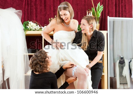 Bride at the clothes shop for wedding dresses, she is choosing a dress and wears a garter