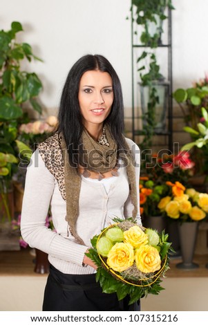 Female florist in flower shop or nursery with yellow roses
