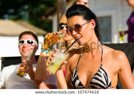 People at beach drinking having a party, woman or girl in front drinking cocktail