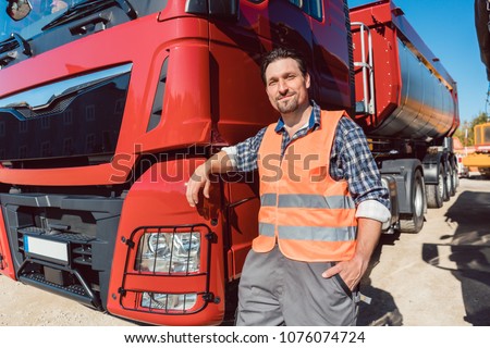 Truck driver in front of his freight forward lorry looking at camera