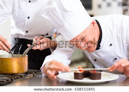 Cook, the pastry chef, in hotel or restaurant kitchen cooking, he is finishing a sweet dessert